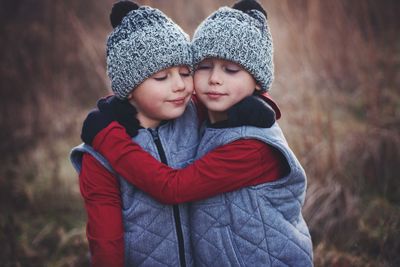 Twin brothers wearing knit hats embracing