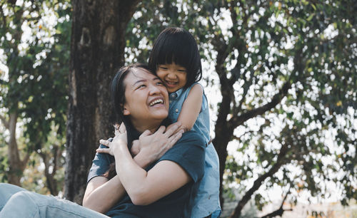 Happy mother and daughter against trees