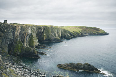 Scenic view of sea by cliff against sky