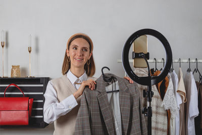 Woman millennial fashion stylist records fashion video on smartphone with ring lamp