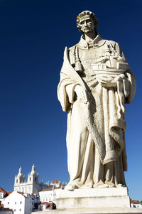 Sao vicente statue by monastery of sao vicente de fora church against clear blue sky