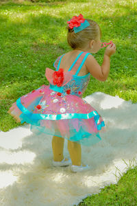 Rear view of cute toddler blowing bubbles while standing on rug at park