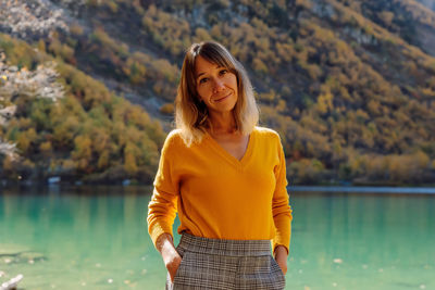 Portrait of young woman standing against lake