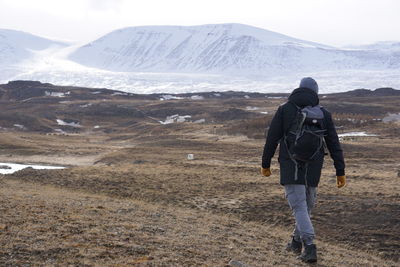 Rear view of man standing on snow covered land