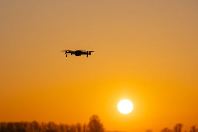 Low angle view of airplane flying against sky during sunset