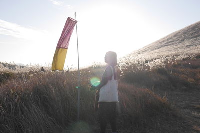 Rear view of girl standing on field against sky