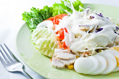 High angle view of salad with boiled egg and meat in plate on table