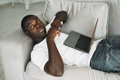 Man with laptop while lying down on sofa