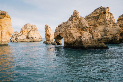 Rock formation in sea against sky