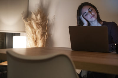 Young woman using laptop on table at home