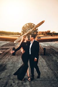 Full length of man with woman standing in airport against sky