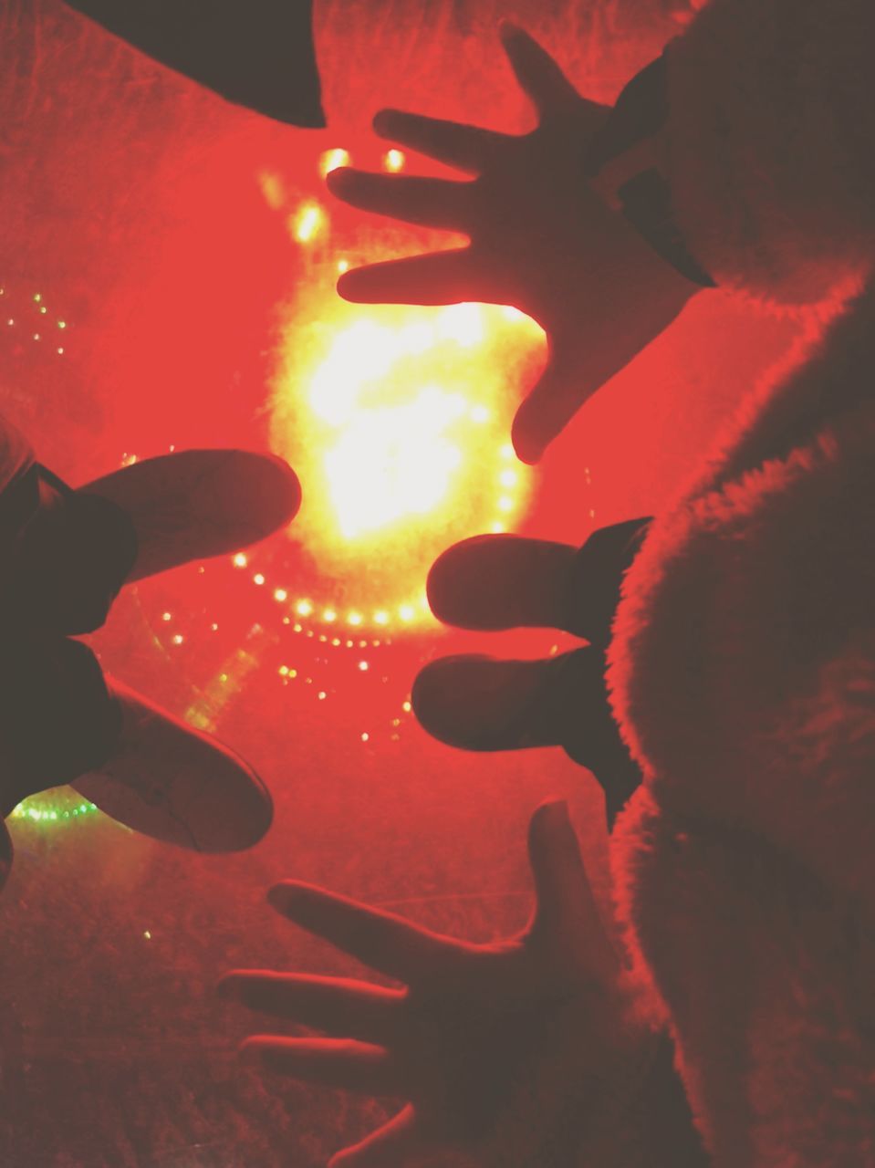 CLOSE-UP OF HANDS AGAINST ILLUMINATED LIGHT