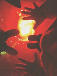 Close-up of hands against illuminated light at night