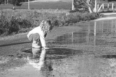 Girl in wellies playing in a puddle on the road