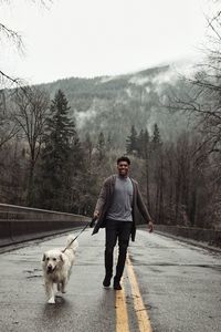 Portrait of man with dog walking on bare trees