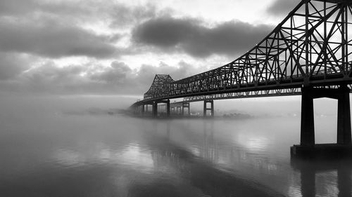 Bridge over river against cloudy sky