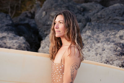 Beautiful, fit woman with surfboard on beach in tofino