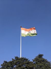 Low angle view of flags against clear blue sky