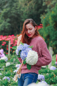 Close-up of woman with pink flower standing against plants