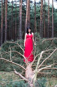 Portrait of woman standing on fallen tree in forest