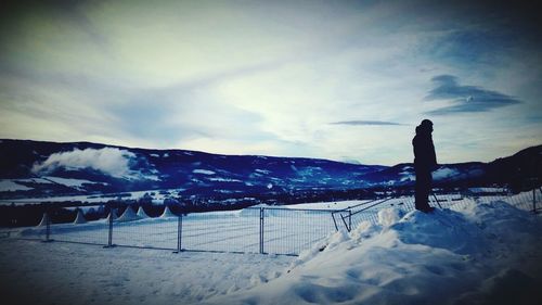 Man standing on snow covered landscape against sky