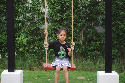 Asian cute girl sitting on a winging in a beautiful garden