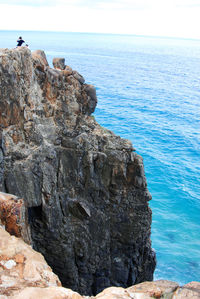 Rock formation by sea against clear sky