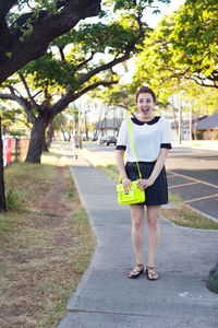 Full length of young woman standing against tree