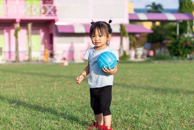 Cute girl playing with ball on field