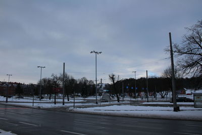 Road by trees against sky in city