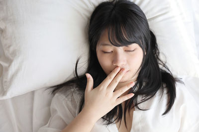 Young woman looking away while lying on bed at home