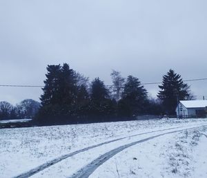 Snow covered land by trees against sky