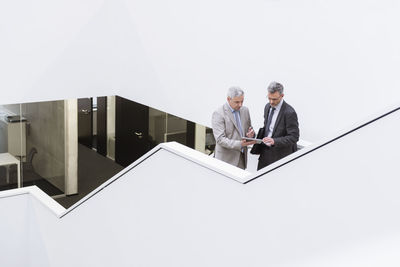 Two businessmen having an informal meeting, using digital tablet