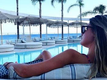 Woman relaxing on swimming pool against sea