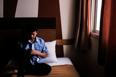 Young man using mobile phone at home