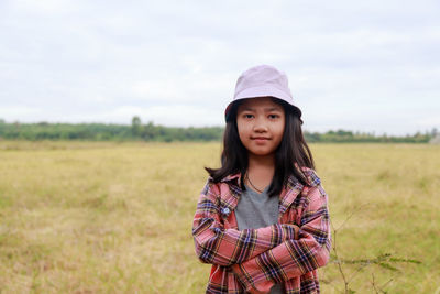 The little asian girl stands confidently with her arms crossed at the tropical farm field,