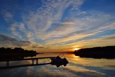 Silhouette boat in lake against sky during sunset