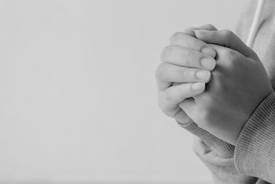 Midsection of child praying against white background