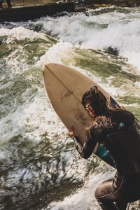 Rear view of woman with surfboard in sea