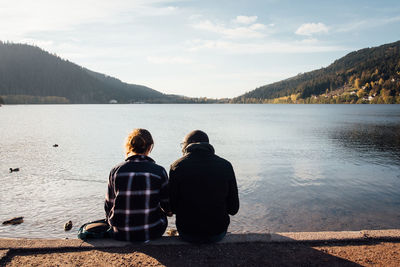 Rear view of woman looking at lake against mountain range