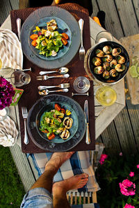 Low section of man standing by food served on table at back yard