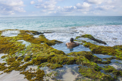 Rear view of man swimming in sea against sky