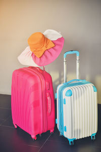 Hat with wheeled luggage against wall