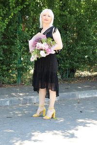 Full length of a smiling woman standing against blue sky