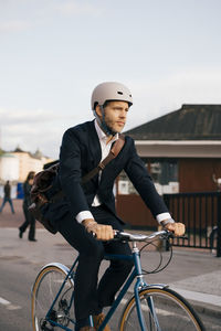 Confident businessman riding bicycle on street in city