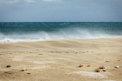 Sea waves rushing towards shore against sky