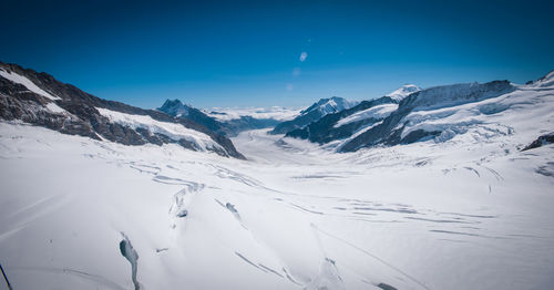 Scenic view of snow covered mountains against clear blue sky