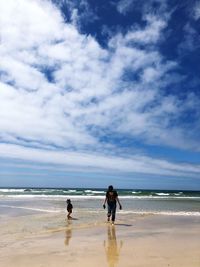 People walking on beach against sky