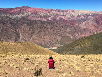 Woman sitting on landscape against sky