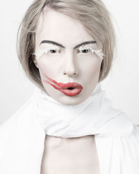 Portrait of beautiful woman with smudge lipstick and false eyelashes against white background